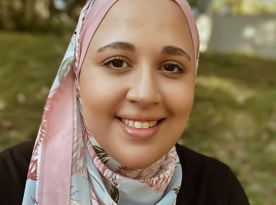 Photo of a Muslim woman smiling, wearing a pink floral hijab.